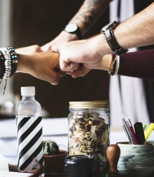 Programa de liderança - pessoas juntando os punhos no centro de uma mesa