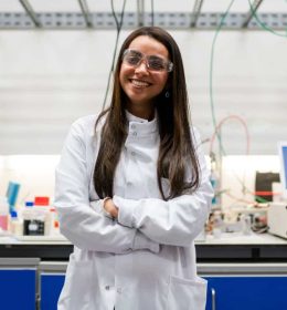 Moça sorridente de jaleco no laboratório olhando para a câmera - bolsas para mulheres nas áreas de ciências